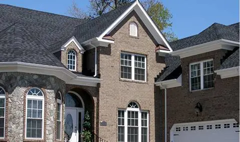 A brick house with two windows and a garage door.