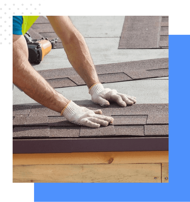 A person with gloves on working on the roof of a house.