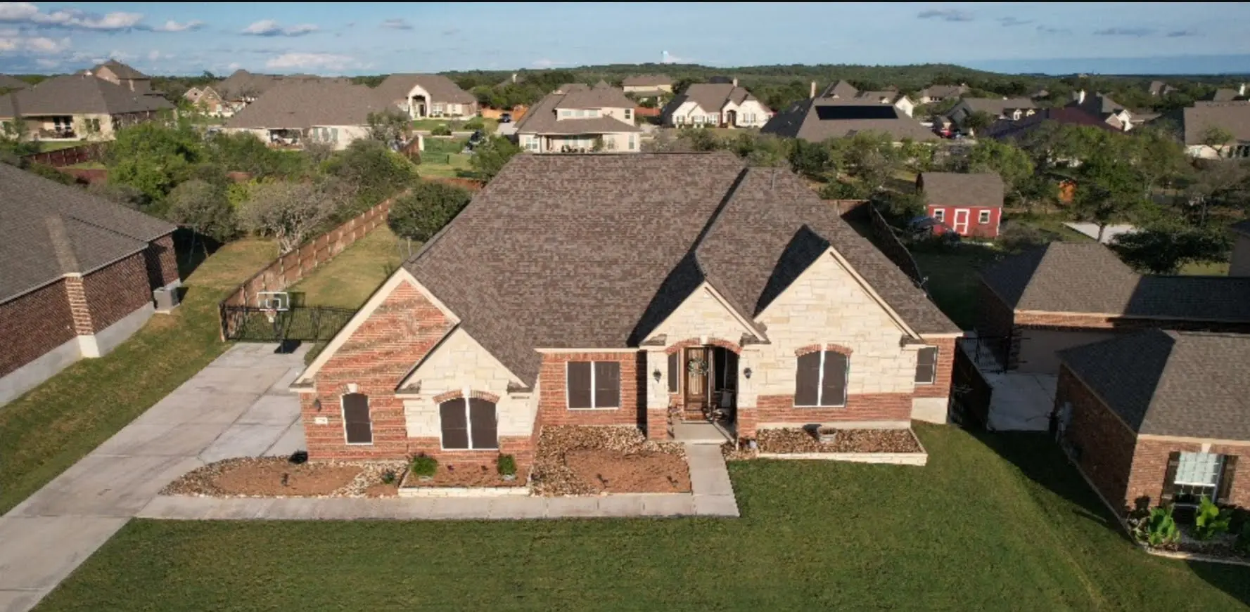 A large brick house with brown roof and green grass.