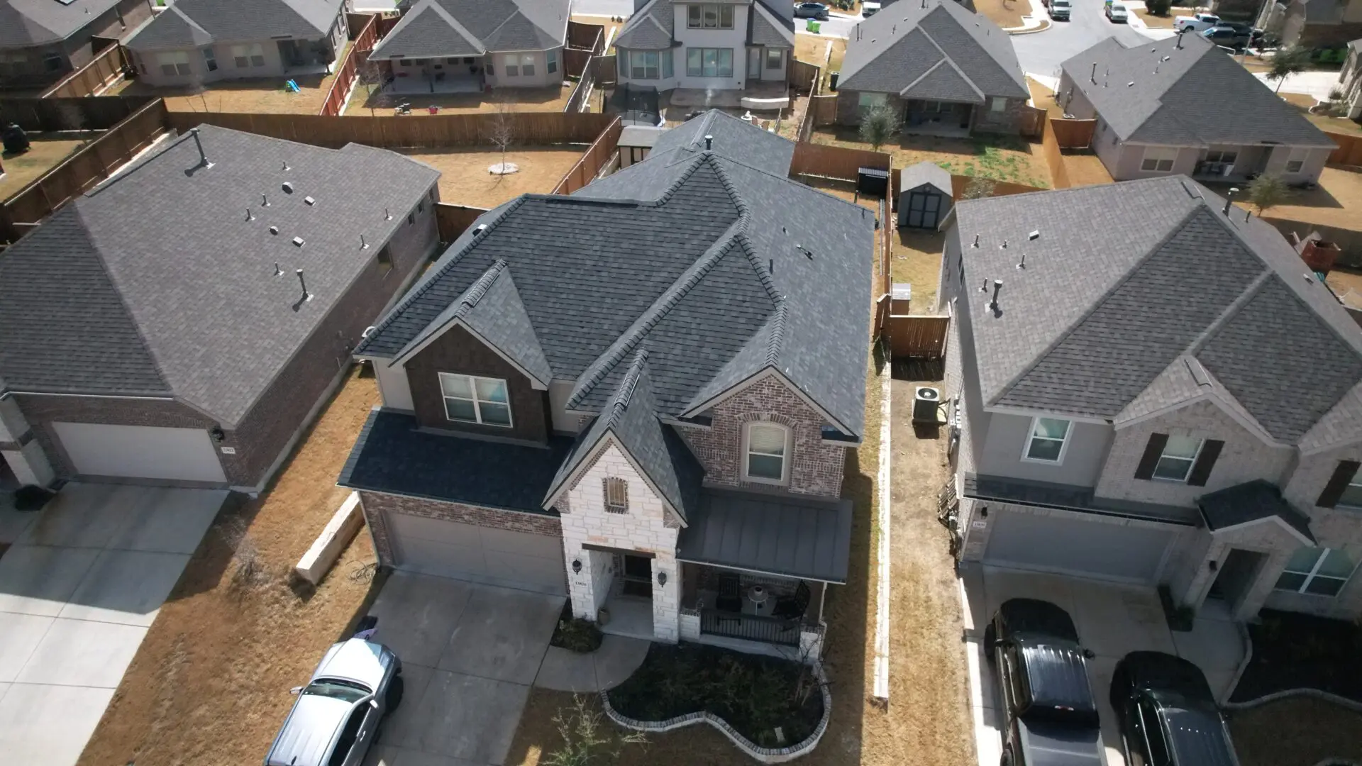 A view of houses from above with cars parked in front.